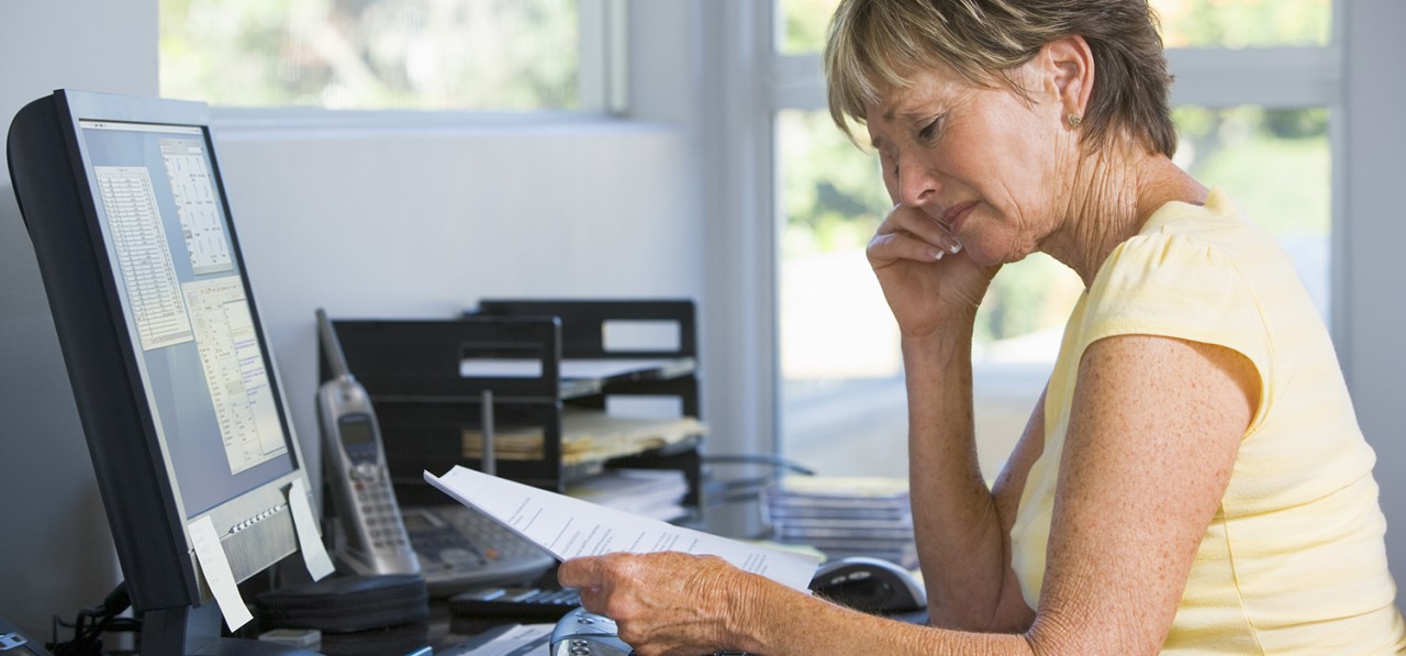 woman-in-home-office-with-computer-and-paperwork-SBI-301053417